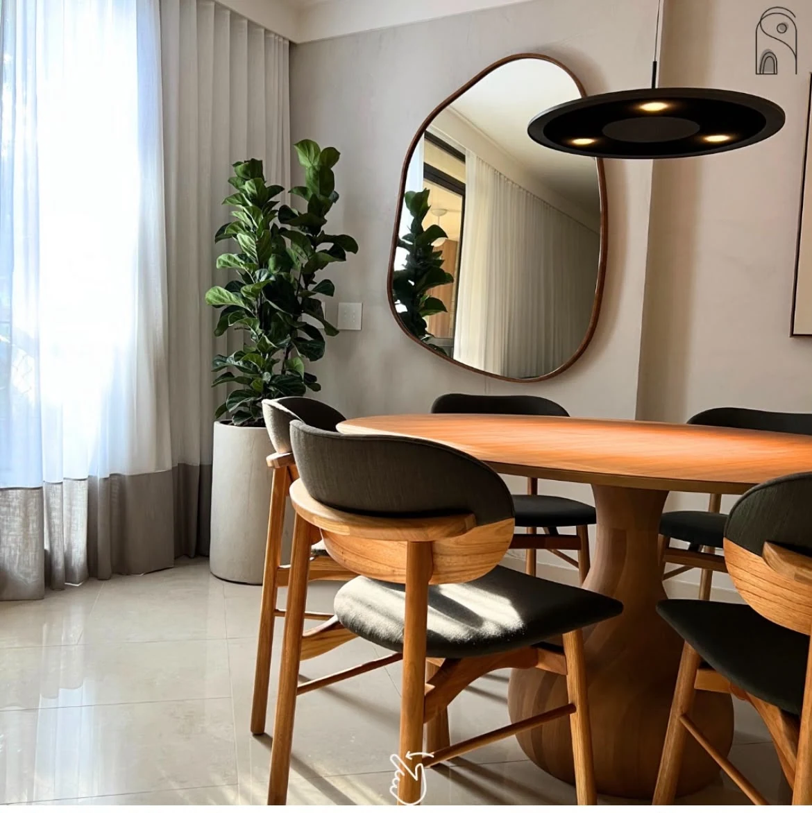 Sala de jantar com cortinas claras, mesa de madeira, cadeiras escuras e espelho de contorno orgânico